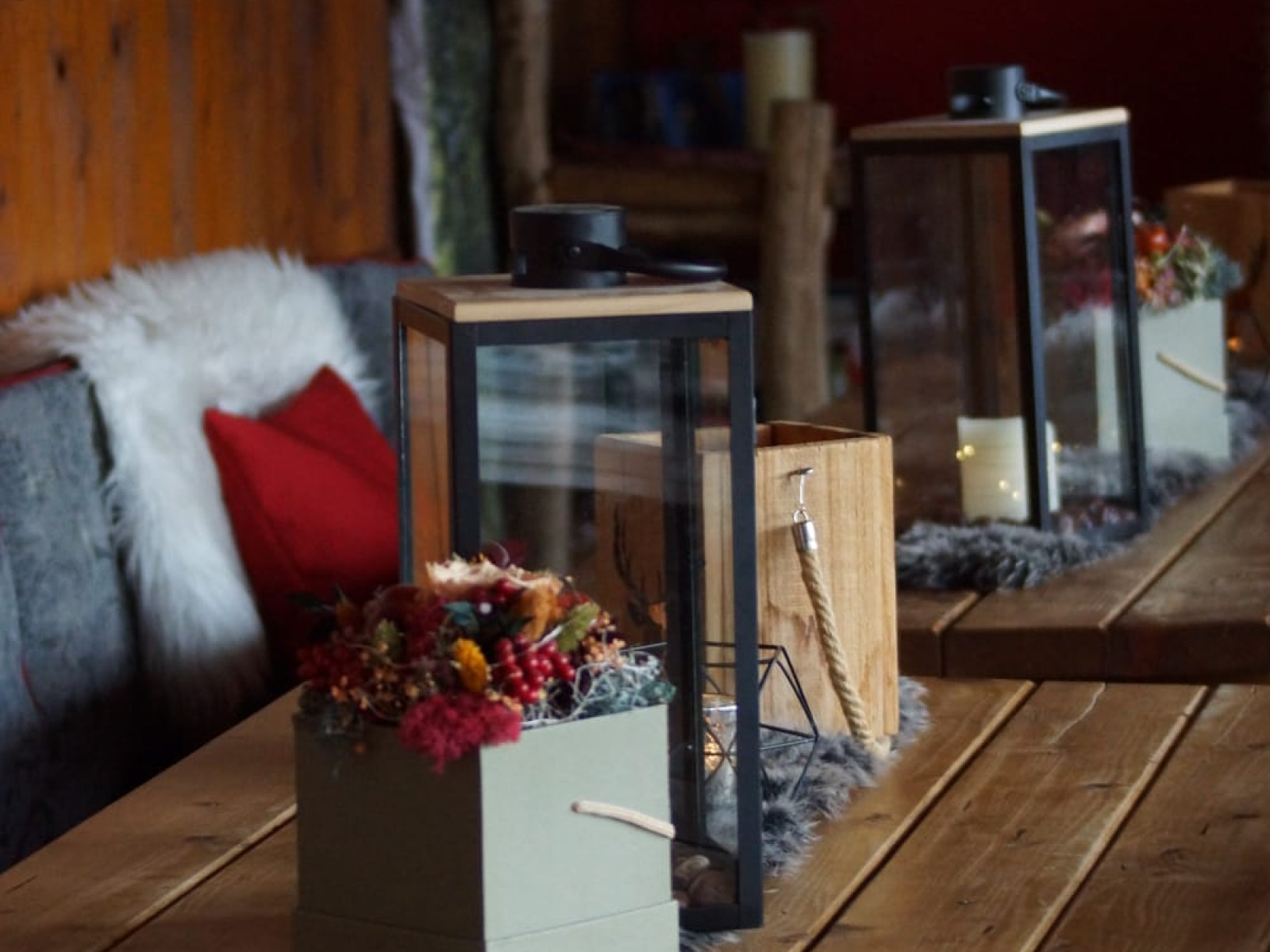 Rustikaler Tisch mit Laternen und Dekorationen in einer Berghütte.