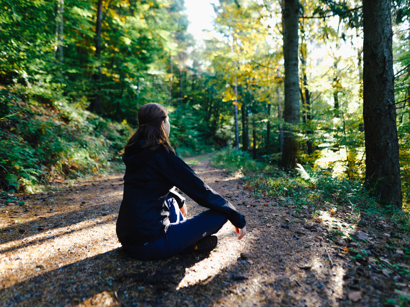 seitenansicht-einer-jungen-frau-die-auf-einem-feld-im-wald-sitzt